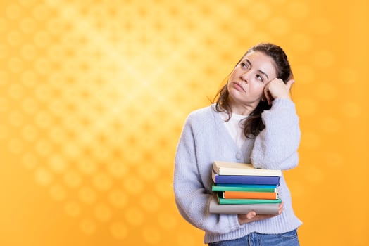 Portrait of relaxed woman daydreaming while holding pile of books, enjoying reading hobby. Person with stack of novels in arms caught in reverie while enjoying leisure time, studio background photo