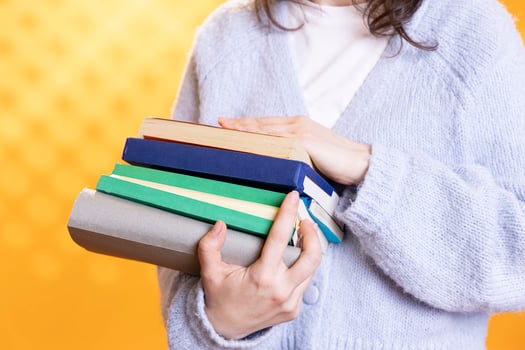 Woman carrying stack of books, gathering information for school exam, isolated over studio background, close up shot. Student holding pile of books, preparing school homework photo
