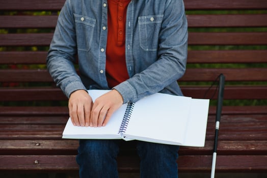 Blind man reading book on bench in park photo