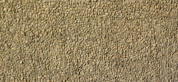 Texture of a stone wall with small round pebble stones. Part of a stone wall as a background or texture photo