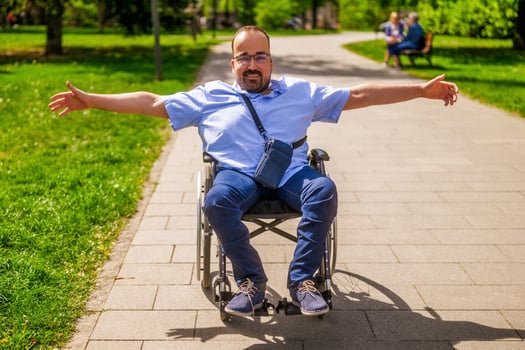 Portrait of happy man in wheelchair. He is enjoying sunny day in city park. photo