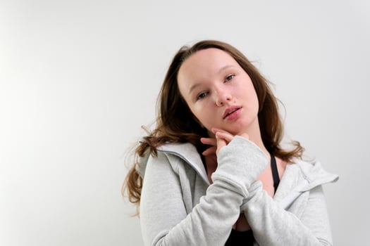 hug yourself young girl posing in front of camera teenager preparing stories and reels smile showing tenderness on white background photo shoot shrug look to side at photographer alone in frame