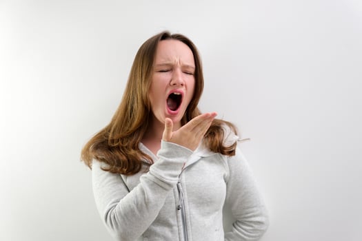 tired yawning in the frame teenage girl tired of studying to work talking yawning with her mouth open covering her face with her hand beautiful hair well-groomed boring life in the studio photo