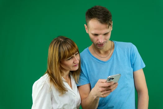 phone call search on the Internet to solve problems a man helps a woman on a green background chromakey spend time in office in nature blue T-shirt white jacket light people touchpad news feed gadget photo