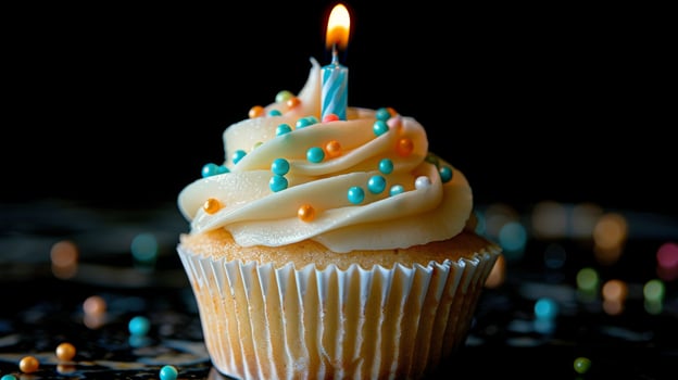 A cupcake with a lit candle on top, surrounded by colorful sprinkles photo