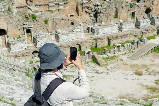 A male tourist enjoys a walk through the amphitheater among the ruins of the ancient city of Perge, in Turkey. The tourist looks around the ancient city of Perge with fascination and takes photographs photo