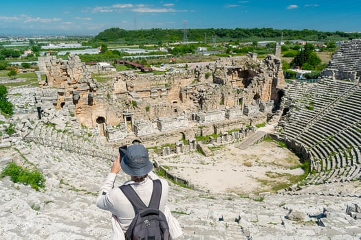 A male tourist enjoys a walk through the amphitheater among the ruins of the ancient city of Perge, in Turkey. The tourist looks around the ancient city of Perge with fascination and takes photographs photo