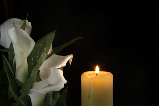 Burning wax candle in close up and white calla lily photo