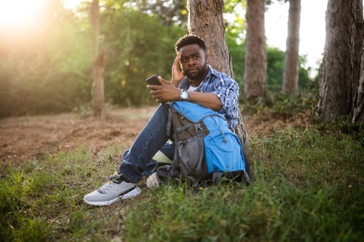 Worried hiker got lost and he is using a phone to find right direction while sitting in the nature. photo