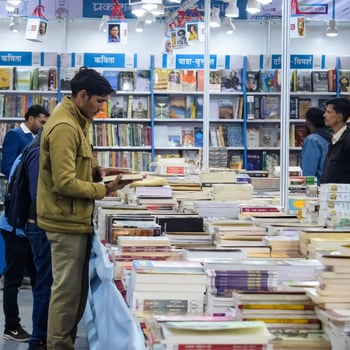 Delhi, India, February 17 2024 - Various age group people reading variety of Books on shelf inside a book-stall at Delhi International Book Fair, Books in Annual Book Fair at Bharat Mandapam complex photo
