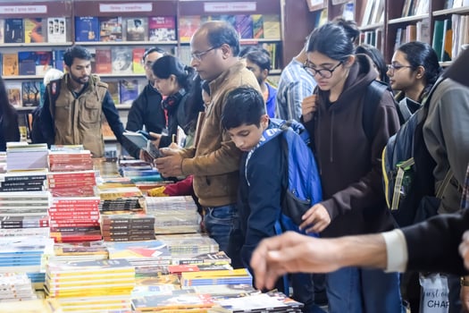 Delhi, India, February 17 2024 - Various age group people reading variety of Books on shelf inside a book-stall at Delhi International Book Fair, Books in Annual Book Fair at Bharat Mandapam complex photo