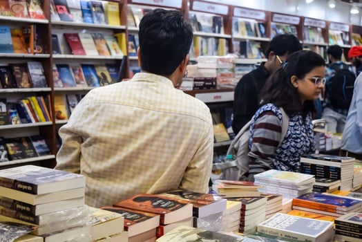 Delhi, India, February 17 2024 - Various age group people reading variety of Books on shelf inside a book-stall at Delhi International Book Fair, Books in Annual Book Fair at Bharat Mandapam complex photo