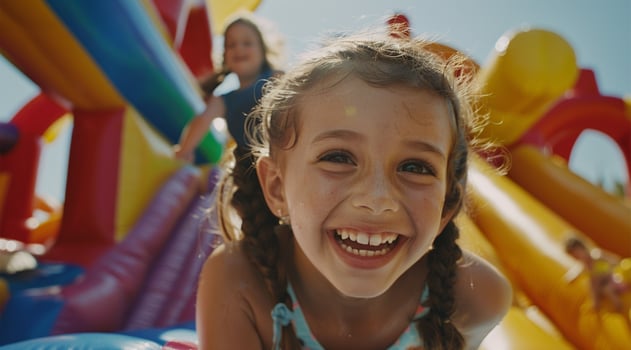 Little girl having fun on an inflatable bouncy castle, with her family watching in the background. photo