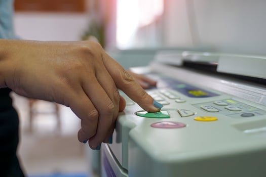 The office secretary presses the button to start the document copying machine to have another copy of the document stored in a file as evidence. photo