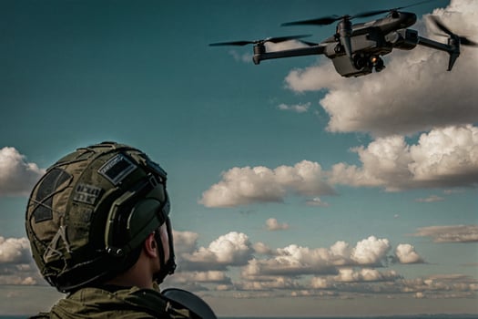 a military man looks at a drone close-up against the background of clouds photo