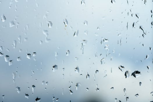 Glass with rain drops against gray background. 1 photo
