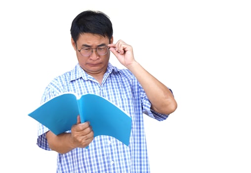 Asian middle aged man wears eyeglasses, tries to read book. White background. Concept , Eyesight health problem. Optometry. Glasses with convex or concave lenses. Myopia.Eye disease. photo