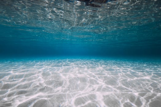 Blue ocean with white sand and sunlight underwater. Transparent ocean background photo