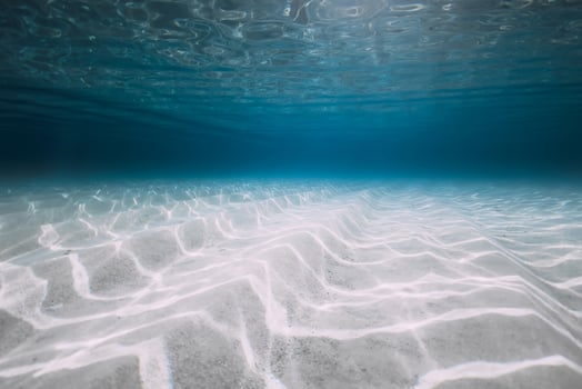 Underwater background in blue ocean with sand photo
