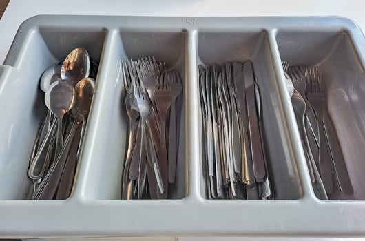 clean cutlery in a cutlery box with knives, forks, spoons in a canteen. photo