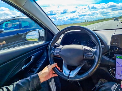 Man hands holding car steering wheel while driving through countryside landscape photo