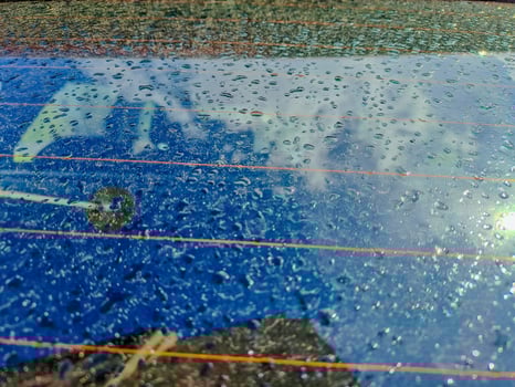Raindrops on the clean car glass image with silver color car on the background photo