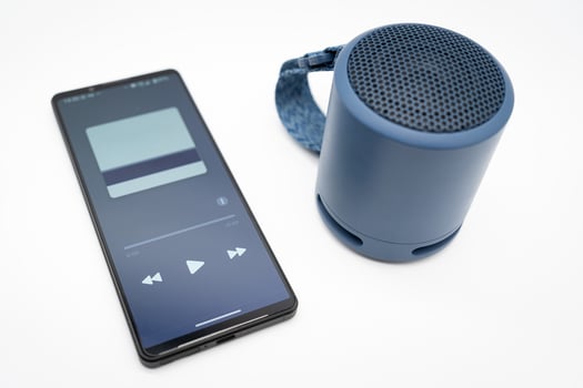Portable wireless blue speaker with smartphone isolated on white background. photo