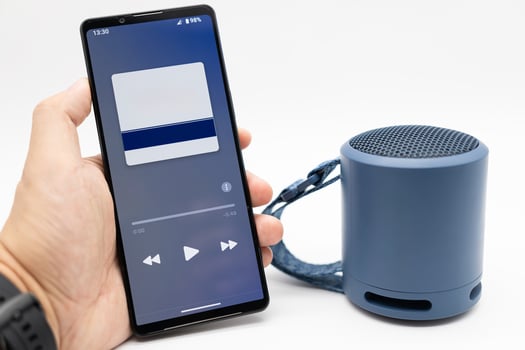 Hand using phone connecting portable speaker. Using bluetooth speaker with smart phone. photo
