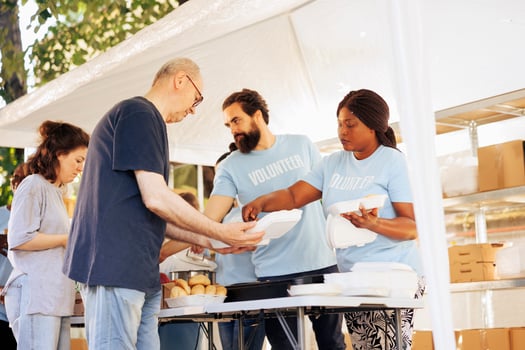 Multiracial team working together at food drive, charitably distributing essential items to less fortunate. Multiethnic people wearing blue t-shirts providing hunger relief and volunteer assistance. photo