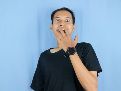 Shocked and surprised face of Asian man in isolated on blue background. photo