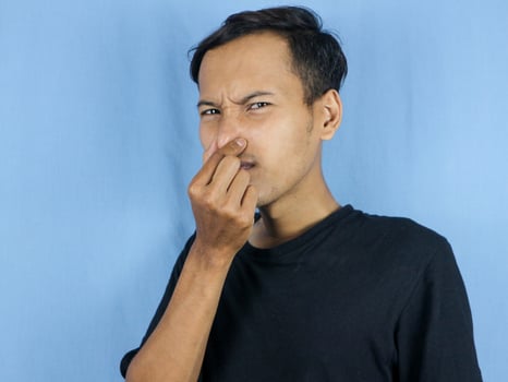 gesture handsome Asian man smelling something stinky and disgusting, intolerable smell photo