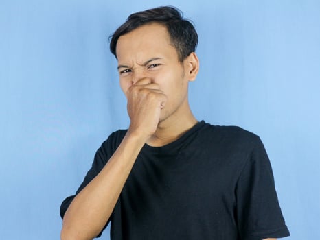 gesture handsome Asian man smelling something stinky and disgusting, intolerable smell photo