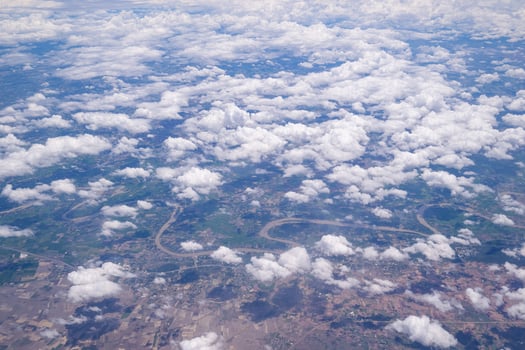 Aerial view of agricultural field, river, and clouds are seen through the airplane window photo