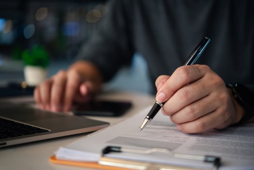 A businessman's hands with a pen over documents, analysis at the workplace. photo