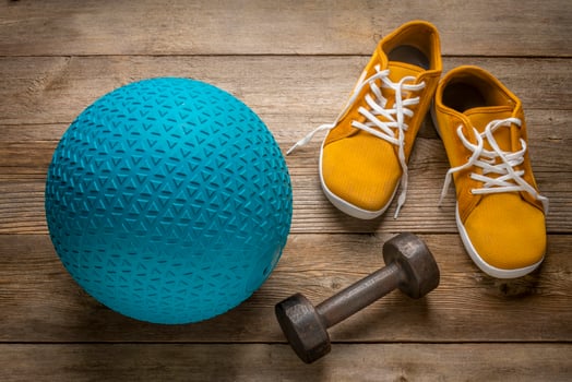 heavy rubber slam ball filled with sand, iron dumbbell and minimalist barefoot sneakers on a rustic wooden deck, exercise and fitness concept photo