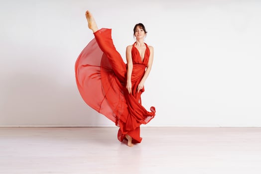 Dancer in a red flying dress. Woman ballerina dancing on a white studio background photo