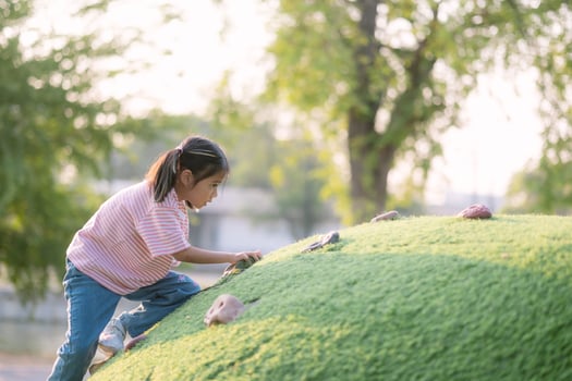 A young girl is climbing a grassy hill photo