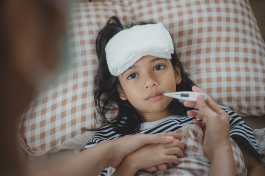 A young girl is being checked for a fever by a woman photo