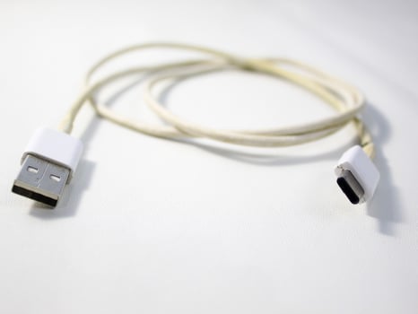 Close up the white broken smartphone usb cable on white wooden background. photo