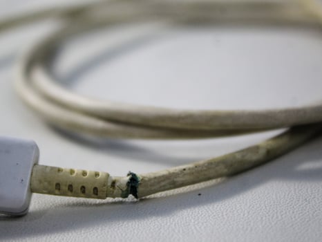 Close up the white broken smartphone usb cable on white wooden background. photo
