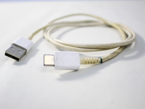Close up the white broken smartphone usb cable on white wooden background. photo