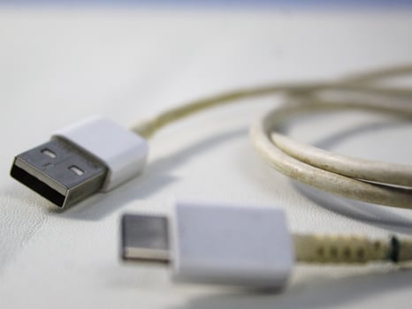 Close up the white broken smartphone usb cable on white wooden background. photo
