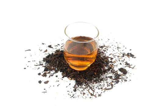 a glass of tea on dry black tea leaves photo