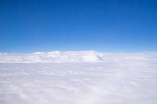 Aerial view of sky seen through the airplane window. Bright blue sky and white clouds with skyline background. Space for text photo