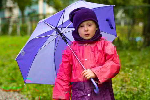 Child with an umbrella walks in the rain. Little boy with umbrella outdoors photo