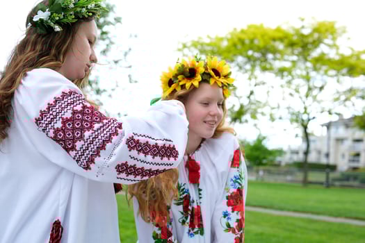 braiding rusu braids a young girl in an embroidered shirt of a traditional Ukrainian shirt weaves pigtails to friend under wreath sit in park spend pleasant time outdoors peace peace peace in Ukraine photo
