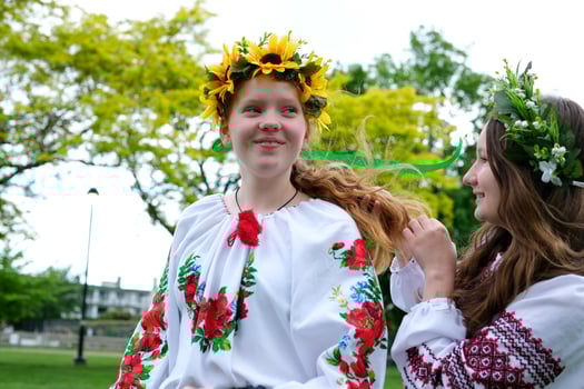 girl are sitting in park waiting for holiday to weave hair braid pigtail wreaths of flowers on head help friend tenderness beauty young hairdresser young women are preparing for celebration photo