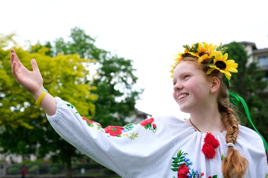 young red-haired girl in a wreath of sunflowers outdoors in park garden in embroidered Ukrainian vyshyvanka shirt with red braid with ribbons in hair Ukraine Peaceful Time of happiness joy and peace photo