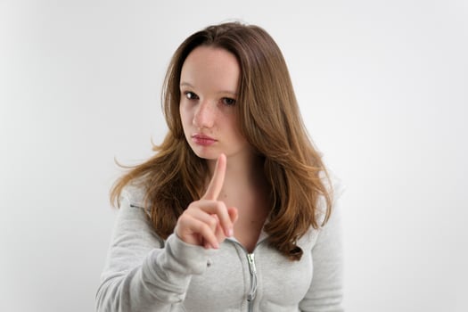 young beautiful girl teenager raised her index finger up alert think be attentive have an idea listen to me she wears a tracksuit on a white background European brown hair photo