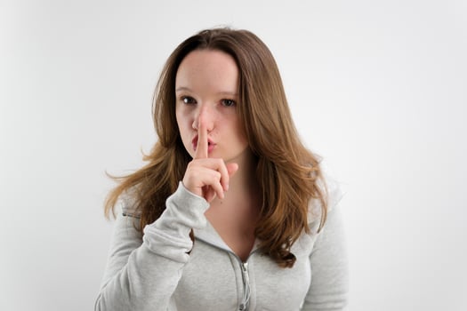 Young woman says ssshhh to maintain silence on a white background photo